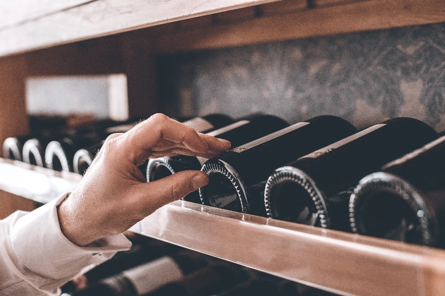 Hand selecting a bottle from a wine cellar